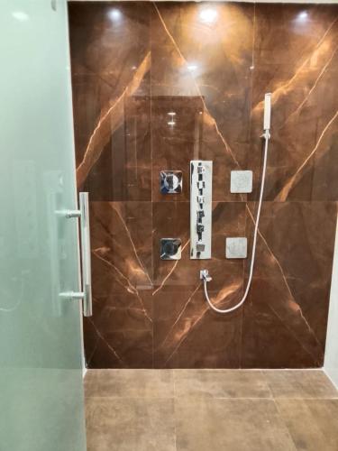 a bathroom with a shower with a brown wall at Hotel Gulmohar Tree in Jāmb