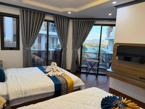 a hotel room with two beds and a flat screen tv at Gu Boutique Hotel - Central Phan Rang in Phan Rang–Tháp Chàm