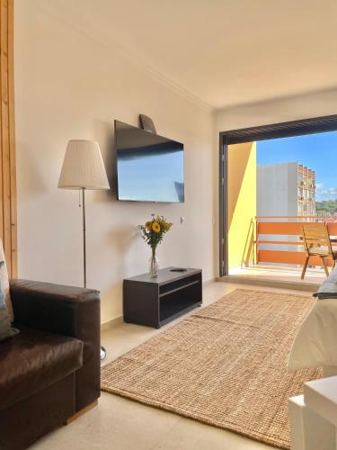 a living room with a couch and a tv at F&V Studio Vilamoura in Quarteira