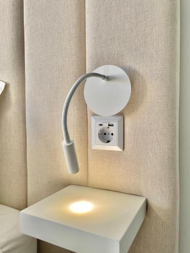 a white lamp on a wall next to a bed at F&V Studio Vilamoura in Quarteira
