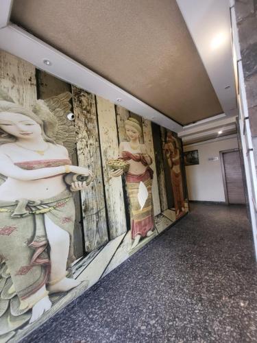 a hallway with paintings of women on the wall at The Mansion Courtyard in Mathura