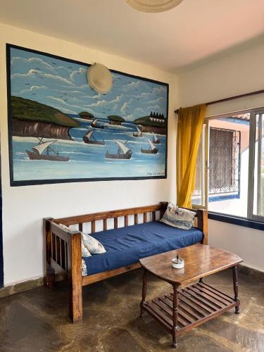 a room with a bed and a table and a painting at Blue House Watamu in Watamu