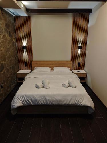 a bedroom with a bed with two slippers on it at Under the rocks luxury in Kalabaka