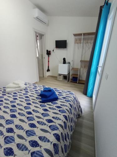 ein Schlafzimmer mit einem Bett mit einer blau-weißen Bettdecke in der Unterkunft CasAmedeo in Calasetta