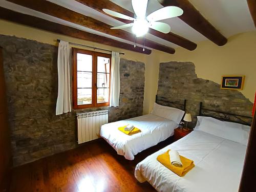 a bedroom with two beds and a ceiling fan at Casa Pirinea Ordesa in Belsierre