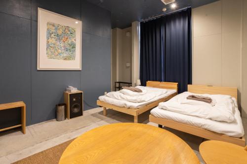 a room with two beds and a table at Hostel STAND BY ME in Fukuoka