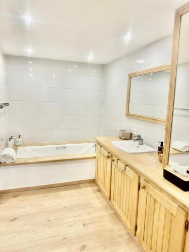 a bathroom with a tub and a sink and a mirror at Le Gîte de Hildegarde in Granges-Aumontzey