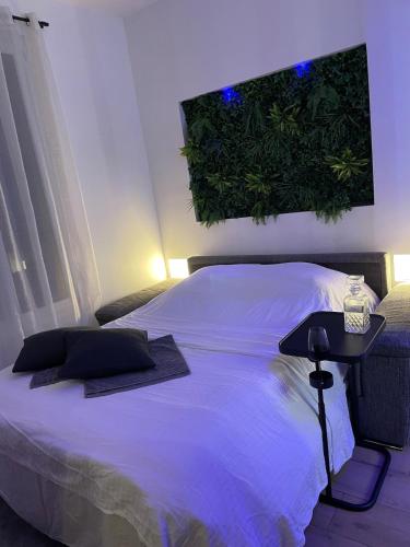 a bedroom with a white bed with a plant on the wall at All in relaxation in Toulouse