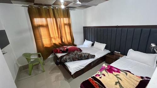 a bedroom with two beds and a green chair at Golden Mud in Srinagar