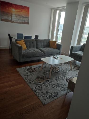 a living room with a couch and a table at Modern 2 bedroom Apt with easy access to Central London, O2, Excel centre and Parking in Woolwich