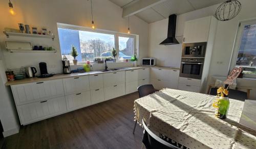 a kitchen with white cabinets and a table and a window at vakantiehuis 't Loreem in Geraardsbergen