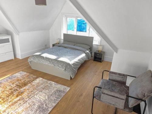 a bedroom with a bed and a chair in a attic at 3-Bed Duplex Flat, Free WIFI & Great Transport Links in Norwood