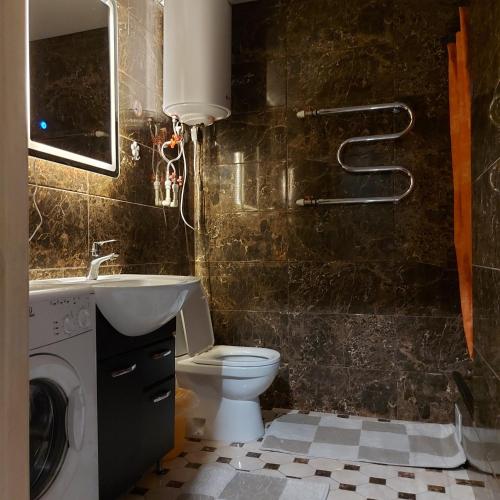 a bathroom with a toilet and a sink and a washing machine at Абзал in Karagandy
