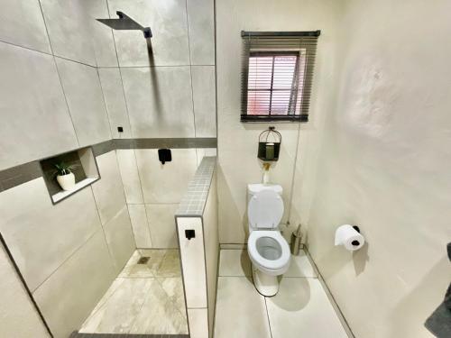 a white bathroom with a toilet and a window at ColtsRest in White River