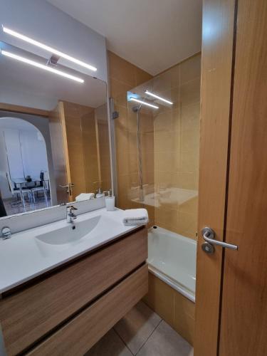 a bathroom with a sink and a tub and a mirror at La Perla Medano 1 in El Médano