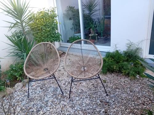 two chairs sitting in front of a house at studio meublé wifi à proximité du tram in Castelnau-le-Lez