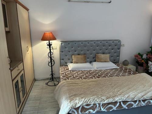 a bedroom with a bed with a headboard and a lamp at Happy Homes 2BHK Second Floor Panchkula in Panchkula