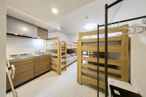 a room with bunk beds and a kitchen with a sink at とりっぱーずホテル方南町 in Tokyo