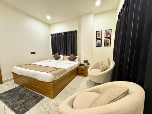 a bedroom with a bed and a chair and a tub at Hotel Sambhavi in Hisua