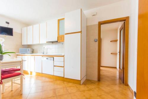 una pequeña cocina con armarios blancos y una mesa en Comano Terme Apart en Comano Terme