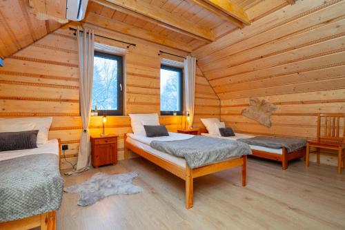 a bedroom with two beds in a log cabin at Luisówka - majestatyczny domek z jacuzzi in Stronie Śląskie