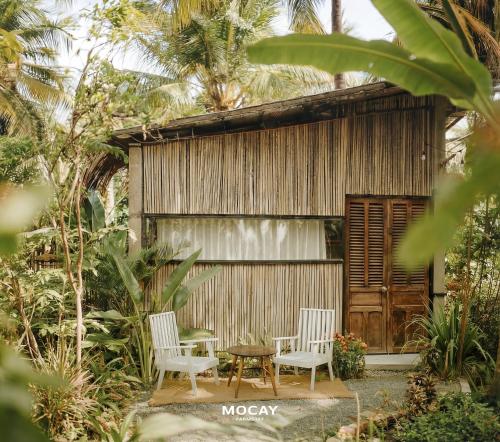 two chairs and a table in front of a building at MOCAY farmstay in Ben Tre