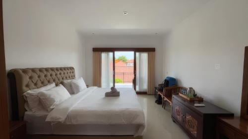 a bedroom with a large bed and a window at LA Homestay sanur in Sanur