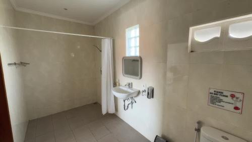 a white bathroom with a sink and a window at LA Homestay sanur in Sanur