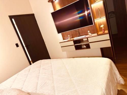 a bedroom with a bed and a flat screen tv at Departamento de lujo inteligente in Cochabamba