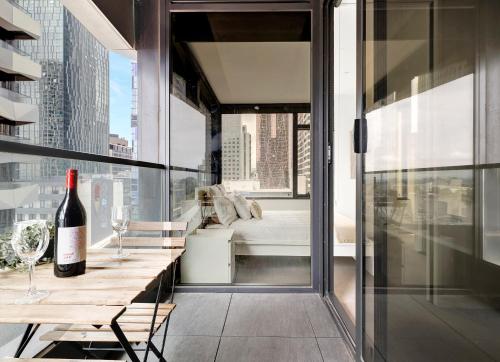 a bottle of wine sitting on a table on a balcony at Luxurious 2BR Apartment - Central CBD Location with Pool, Gym in Melbourne