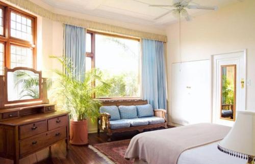 a bedroom with a bed and a chair and a window at Portview and Brenwin Guesthouse in Cape Town