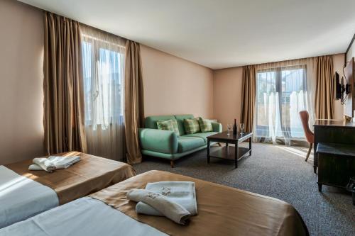 a hotel room with two beds and a couch at Wellness Hotel Bulgaria in Bansko