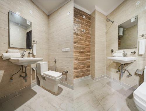 a bathroom with two sinks and a toilet and a mirror at Yashobhoomi Grand in Jāmb