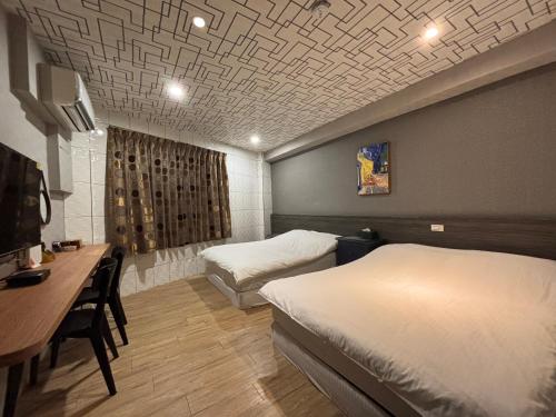 a hotel room with two beds and a desk and a table sidx sidx at 橙橙民宿瑞芳車站 in Ruifang