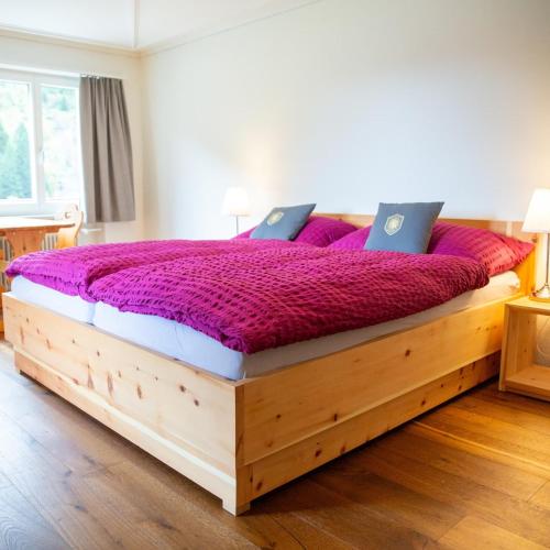 a bedroom with a large wooden bed with purple sheets at Gasthaus Sonne in Urnerboden