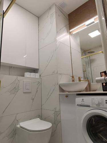 a bathroom with a toilet and a sink and a washing machine at Apartament Kaszmir 3 in Sławno