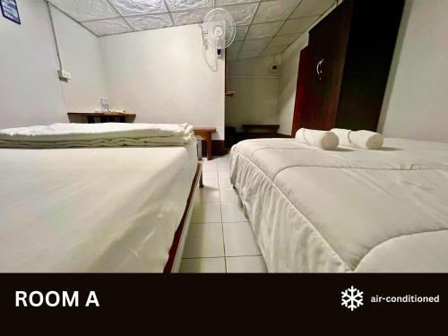 a room with two beds and a white wall at Huean Him Pan Homestay เฮือนฮิมปานโฮมสเตย์ in Ban Mae Pan