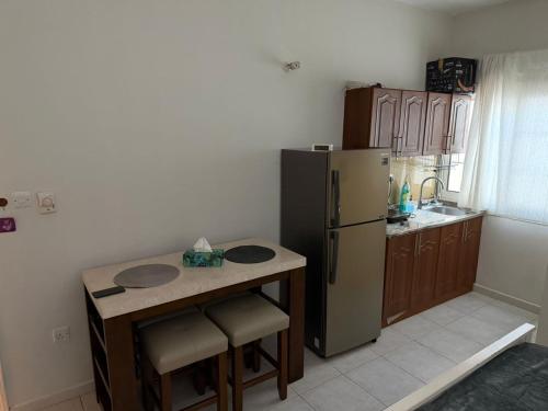 a kitchen with a refrigerator and a table with chairs at Studio Room with Private Bathroom & kitchen in Abu Dhabi