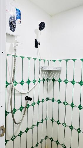 a shower in a bathroom with green and white tiles at Rc Guest House in Phi Phi Islands