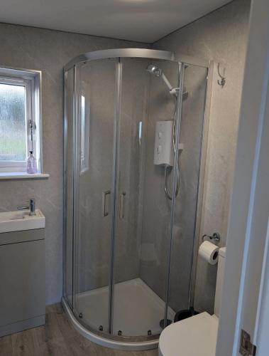 a shower with a glass door in a bathroom at Inverness Ardtower Escapes in Culloden