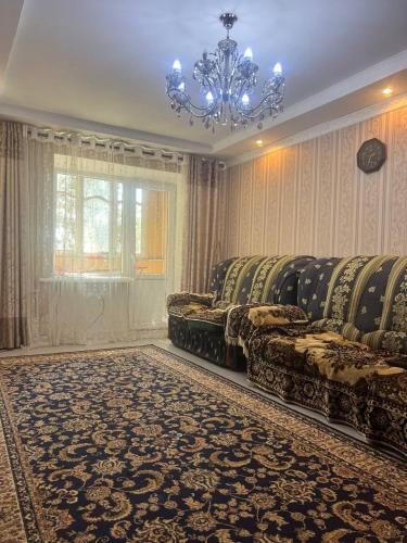 a living room with couches and a chandelier at Квартира у Асели in Karakol