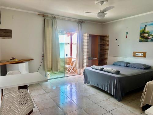 a bedroom with a bed and a table and a window at Pousada Convés das Ondas in Penha