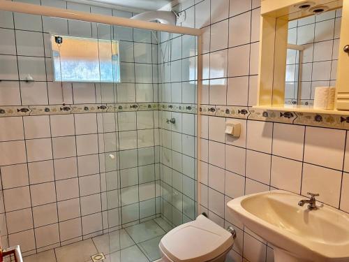 a bathroom with a shower and a toilet and a sink at Pousada Convés das Ondas in Penha