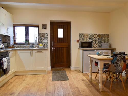 a kitchen with a table and a wooden door at Sparrow - Uk30747 in Acton Trussell