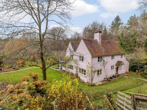 an old white house in the middle of a yard at Highlands Farmhouse in Dallington