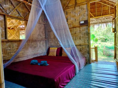 a bed in a room with a mosquito net at Kohmook Money RUEAN PHAI in Trang