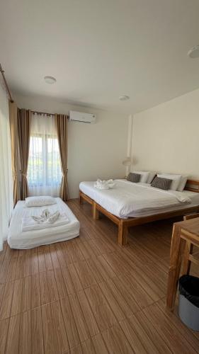 two beds in a large room with wooden floors at The Yard Sukhothai Old Town in Sukhothai
