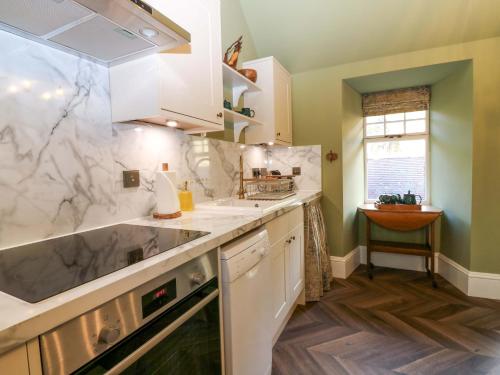 a kitchen with white cabinets and marble counter tops at Braeriach - Mar Lodge Estate in Ballater