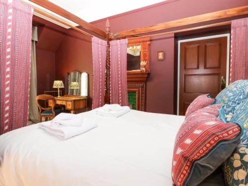 a bedroom with a large white bed with pink walls at Braeriach - Mar Lodge Estate in Ballater