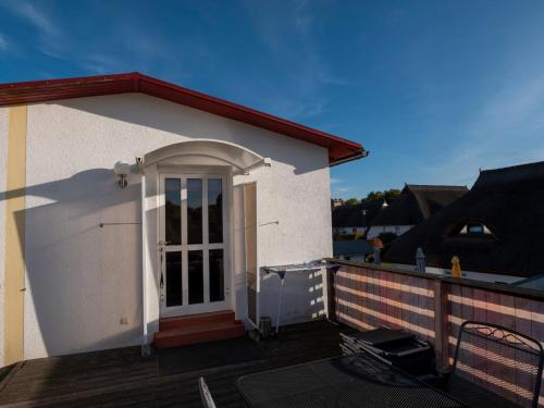 a small white house with a door on a deck at Ferienwohnung Wieck Greifswald in Wieck